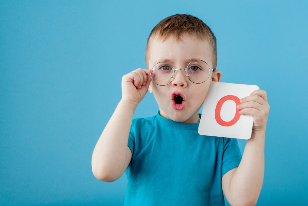 Cute little boy with letter on blue background. Child learning a letters. Alphabet.